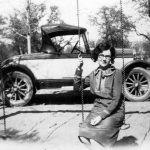 A woman poses while sitting on a swing with a roadster in the background, Blanco, TX